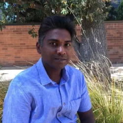 A man in a blue shirt in front of some grasses