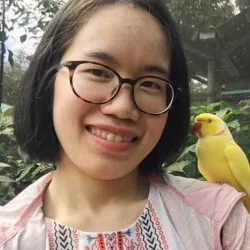 A girl with glasses with a yellow bird on her shoulder